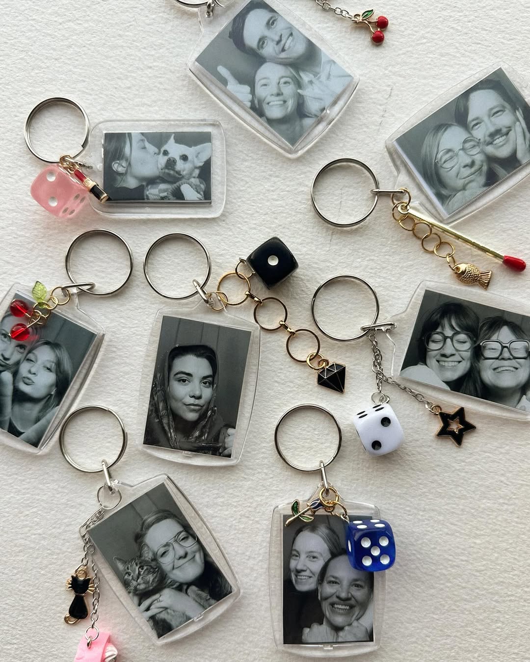 Collection of keychains with black and white photos and various charms on a textured surface.