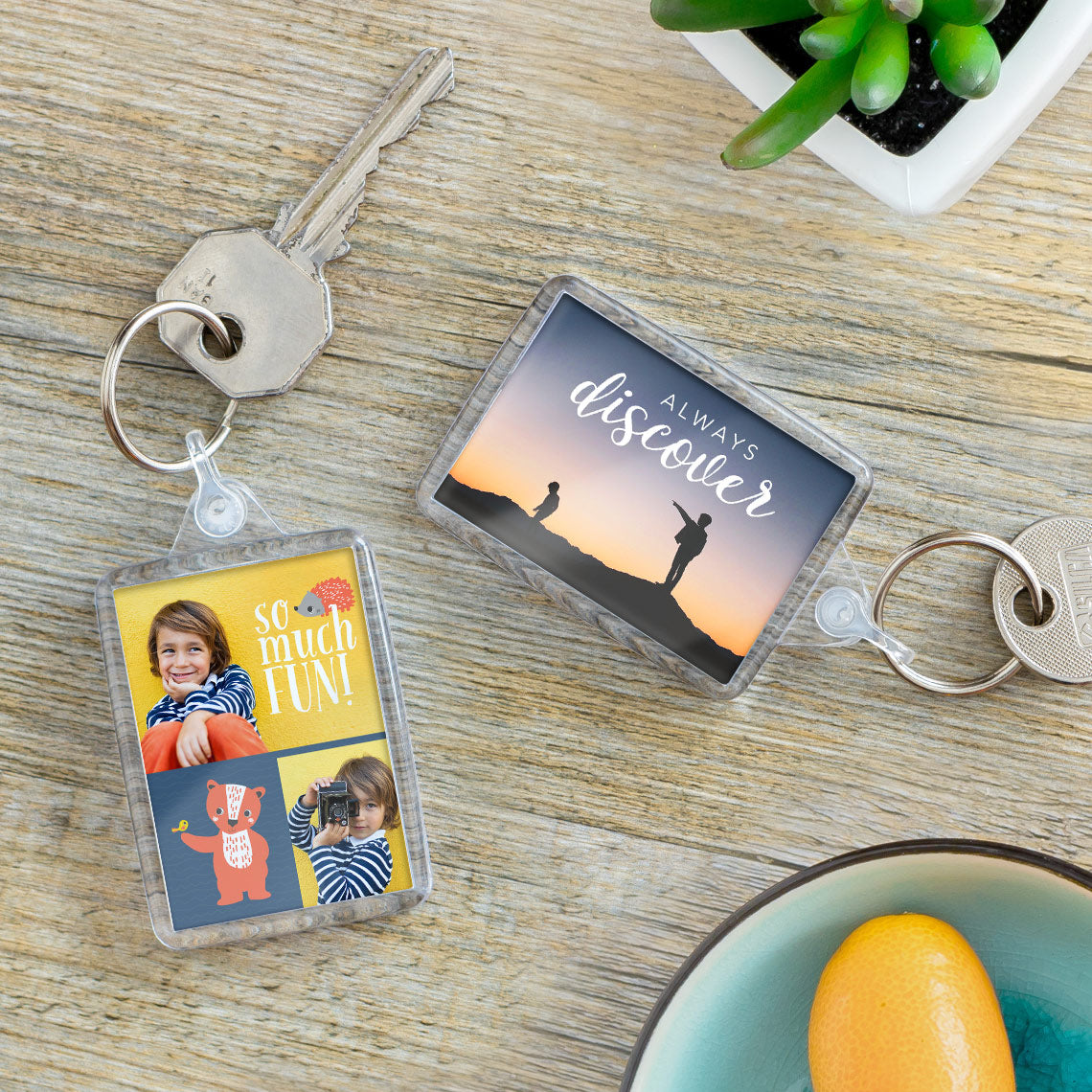 Two keychains on a wooden surface with one featuring a photo of children and the other with a motivational quote.