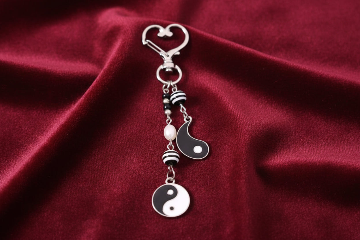 Decorative keychain with yin yang symbol on a beige background